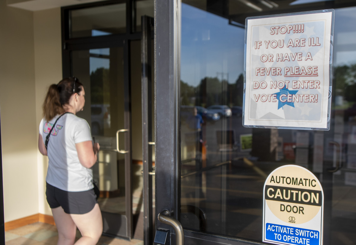 A voter walks past a sign asking people who are sick not to enter the vote center on Tuesday at Mount Pleasant Christian Church in Greenwood. Scott Roberson photo